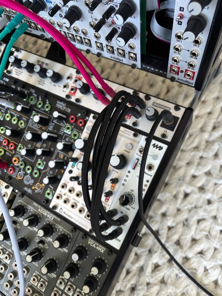 snapshot of a corner of a modular synth showing a cluster of four modules bristling with patch cables. 