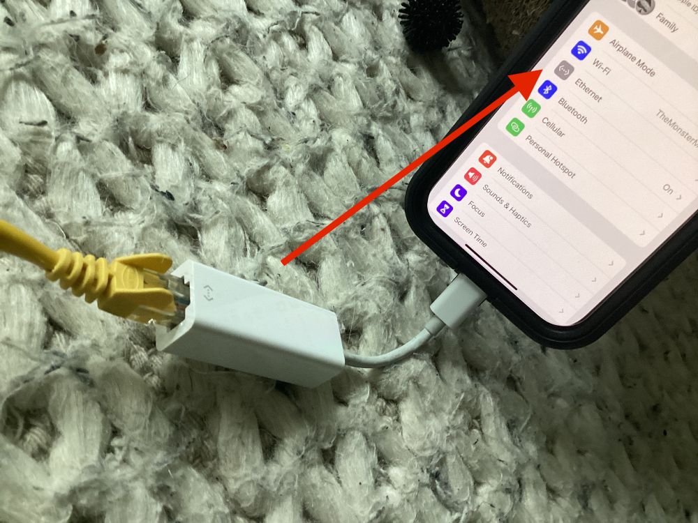 ethernet adapter plugged into USB C on an iphone running iOS 17 with ethernet option visible under settings.