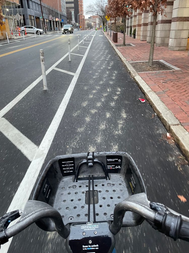 basket of a bikeshare bike going down a bike lane that is pre-treated for a winter storm