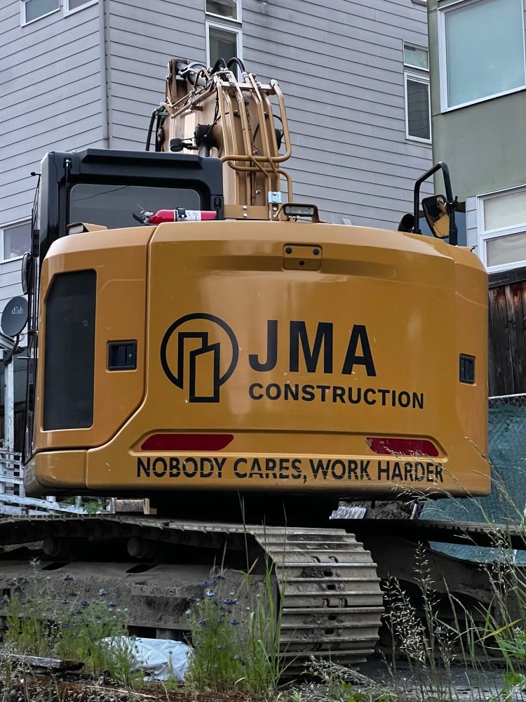 An excavator on a construction site with the words NOBODY CARES, WORK HARDER written on it.