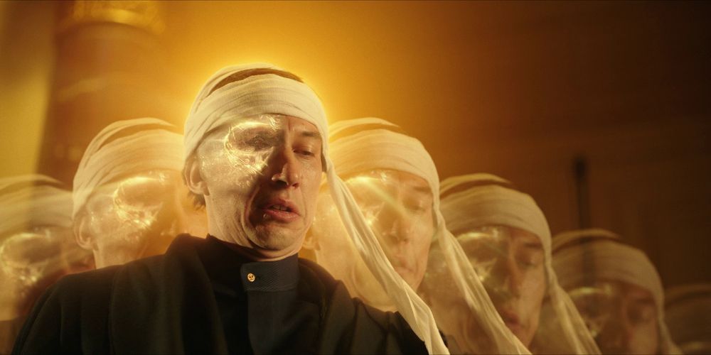 Adam Driver doing a powerful jutsu to have seven ghost selves appear beside him while half his face is glowing because it was replaced with Megalon and he's wearing a white strip of cloth around his head like it's a bandana