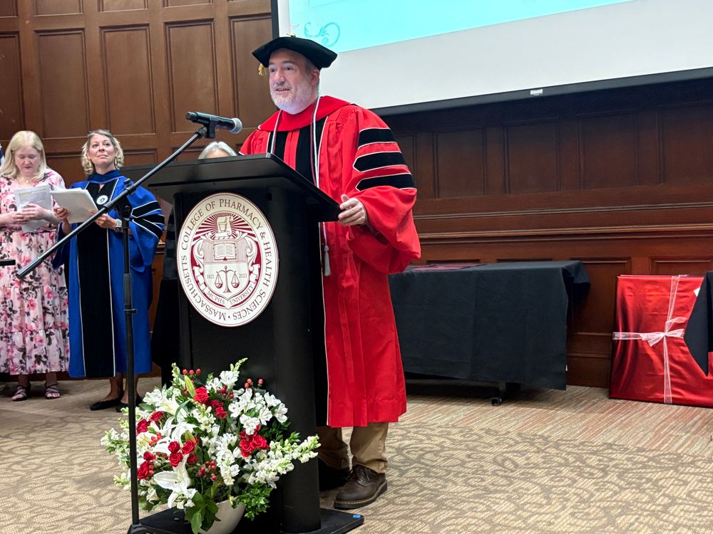 College professor at a podium, wearing full academic regalia. 