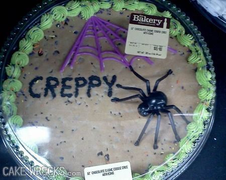 a Halloween cake with a fake spider on it and a spiderweb decoration with black frosting spelled incorrectly, "CREPPY"