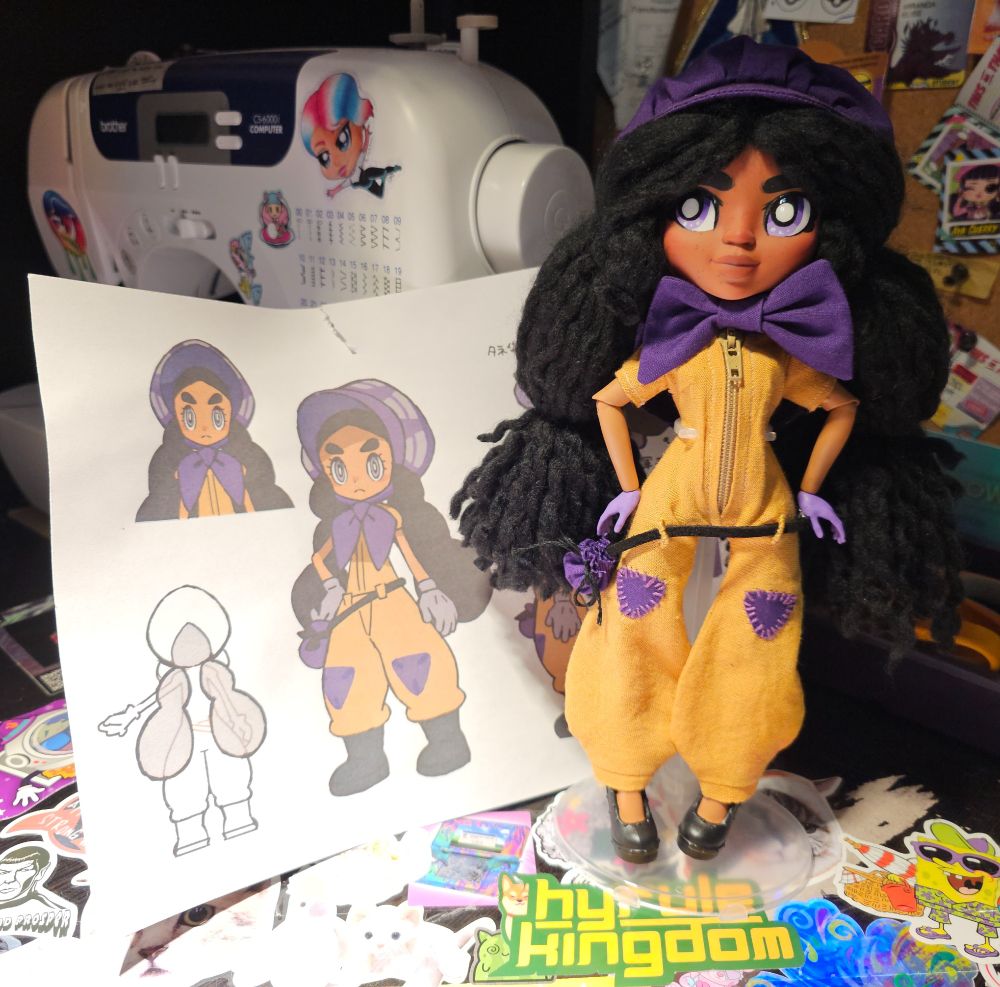 My doll posed next to a printed reference image sheet and my sewing machine. 