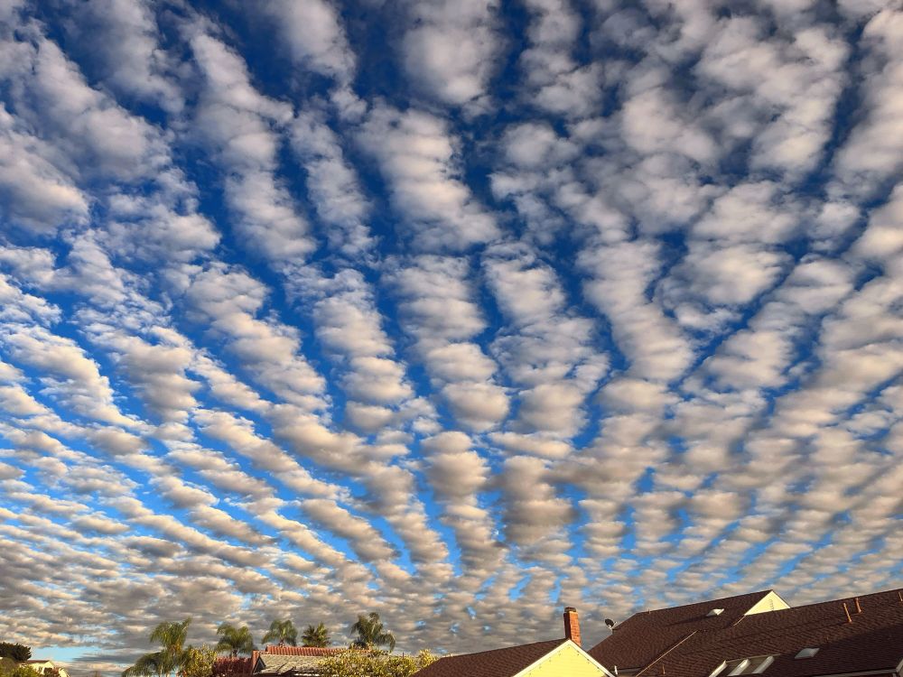 Patterned clouds over houses that appear to be a section of a large spiral 