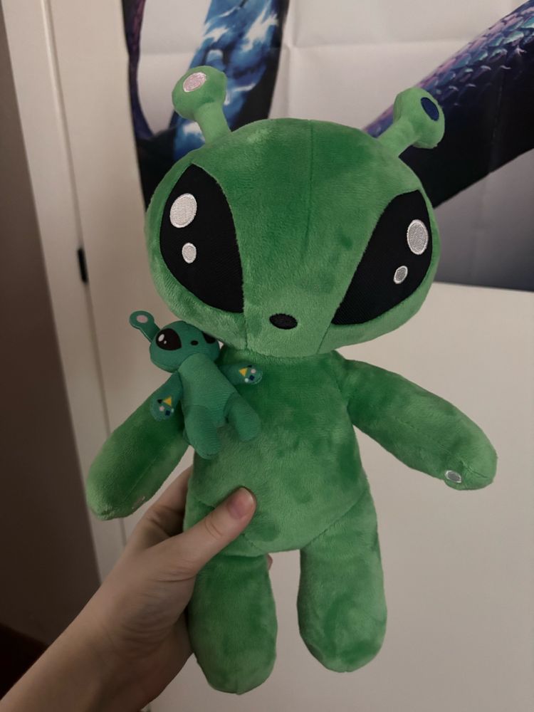 Alien plushie with a smaller alien plushie on its shoulder