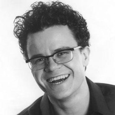 Black and white headshot of the comedian Dominic Holland