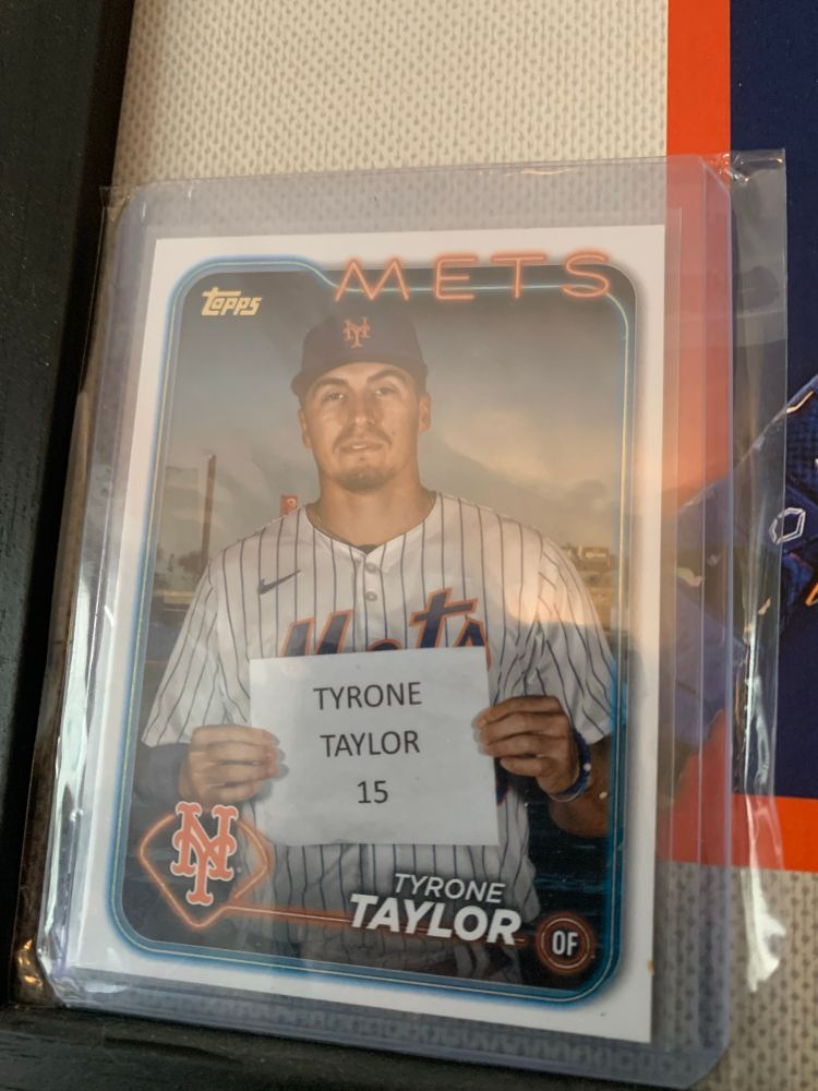 Mets player Tyrone Taylor. He holds up a sign that says: “TYRONE TAYLOR 15”.