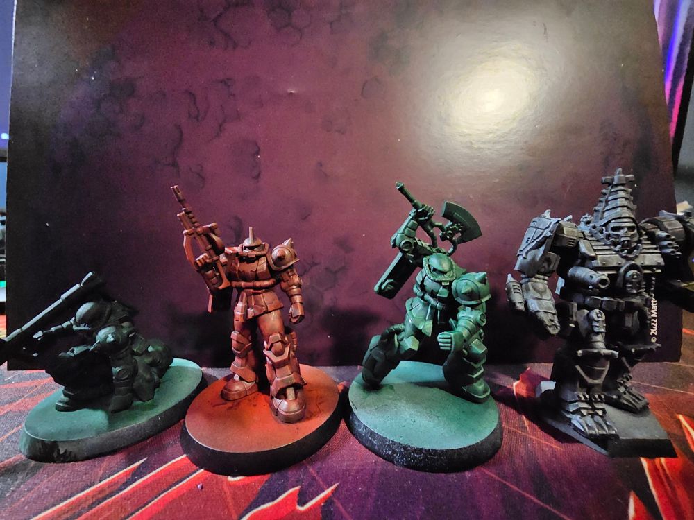 Three Zaku miniatures primed (two green and one red) and a Battletech Gothic Atlas mech.