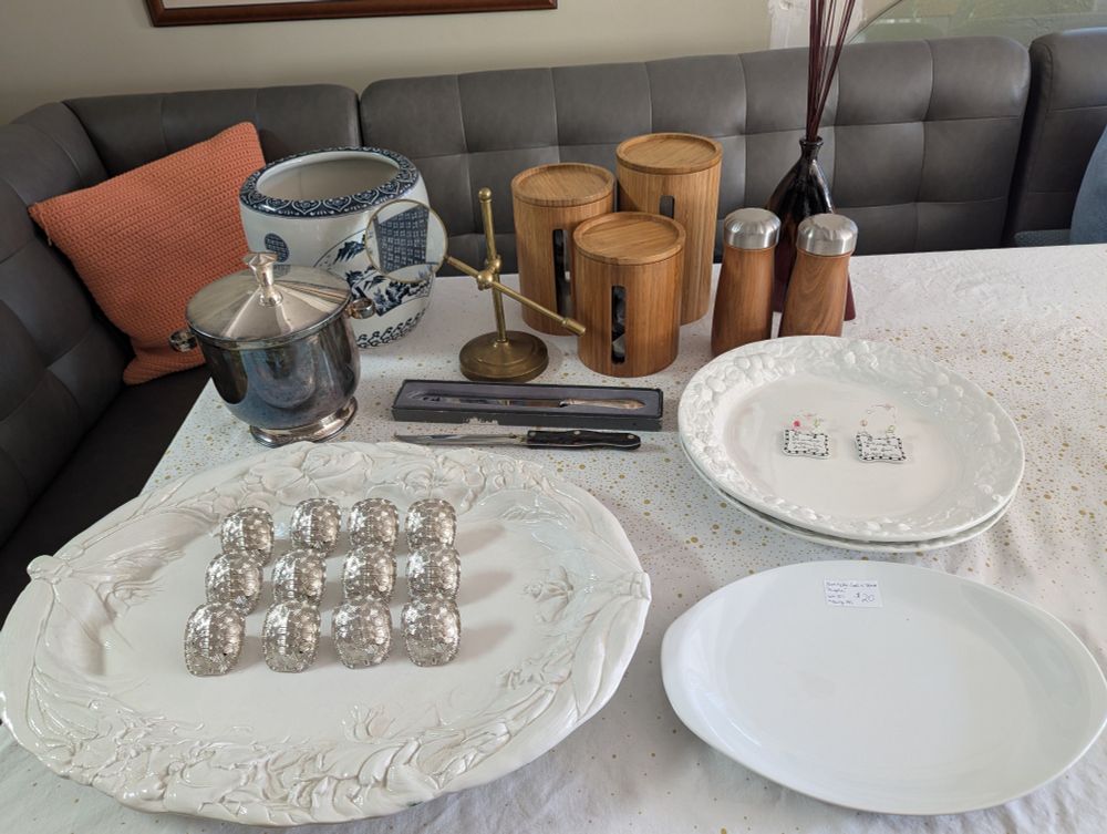 Tablescape with multiple items including canister set, thermoses, four white large platters, silver ice bucket, two very nice knives, a brass magnifying glass on a pole, 12 Arthur Court tortoise napkin rings, and a large porcelain planter. 