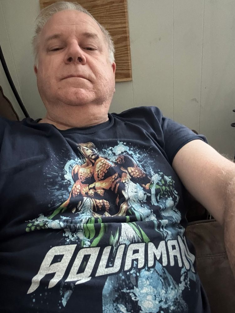 Older white manwith grey hair wearing an Aquaman T-shirt 