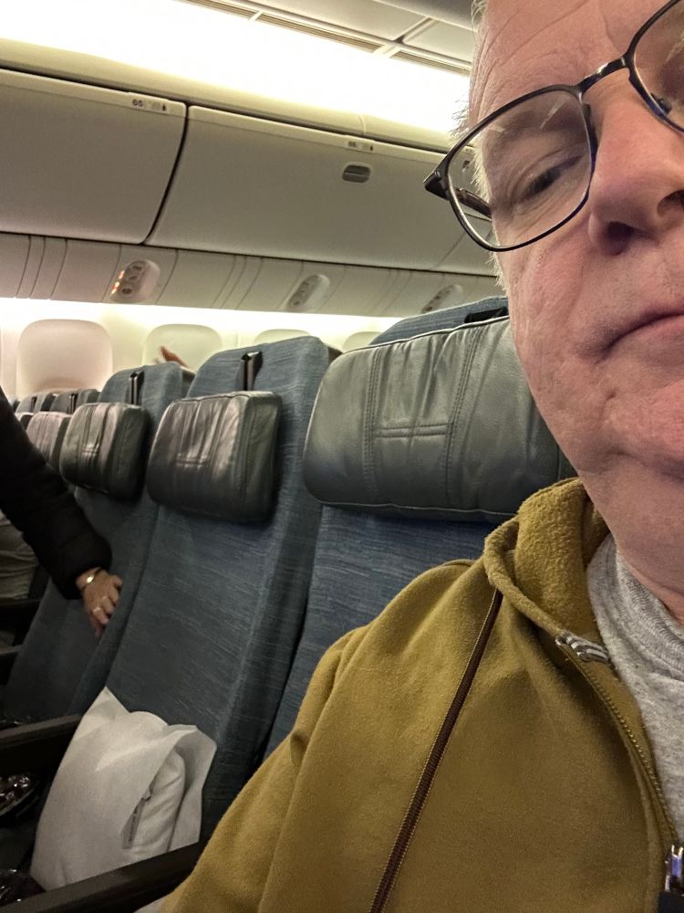 Picture of me on an airplane with two empty seats before me. 