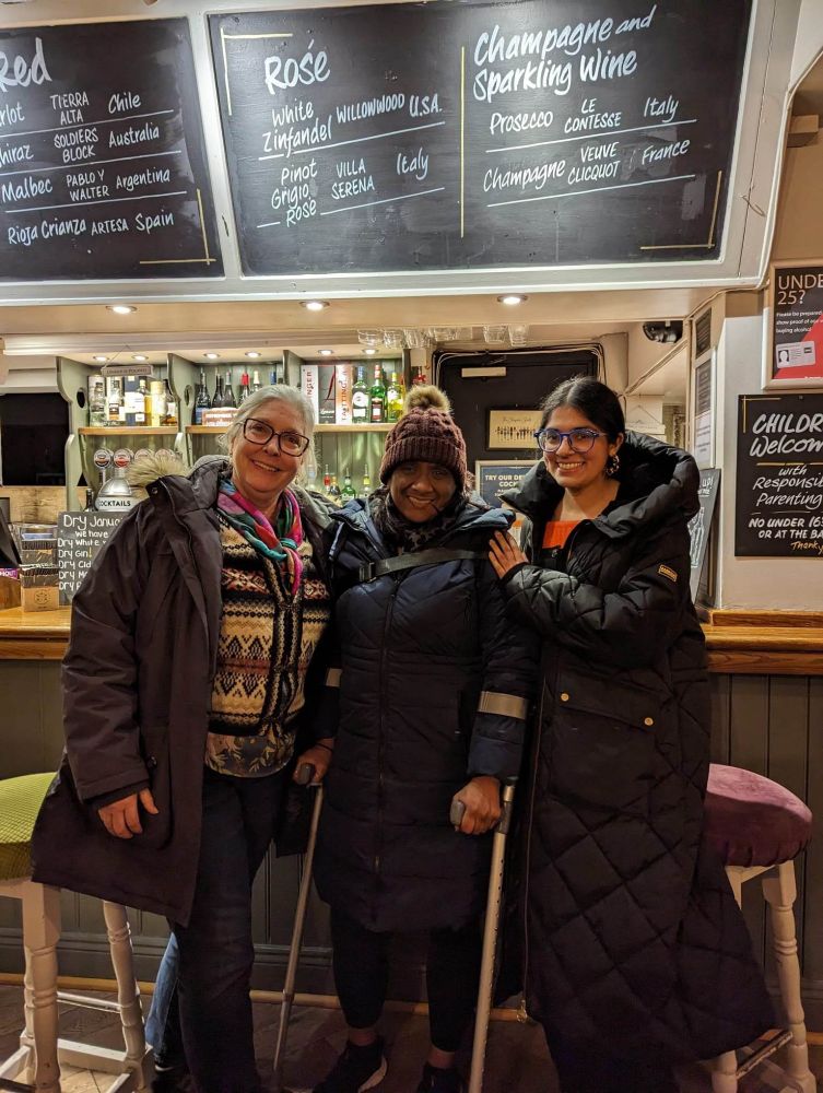 Linnea, Sweta on crutches, and Smita in a pub standing at the bar