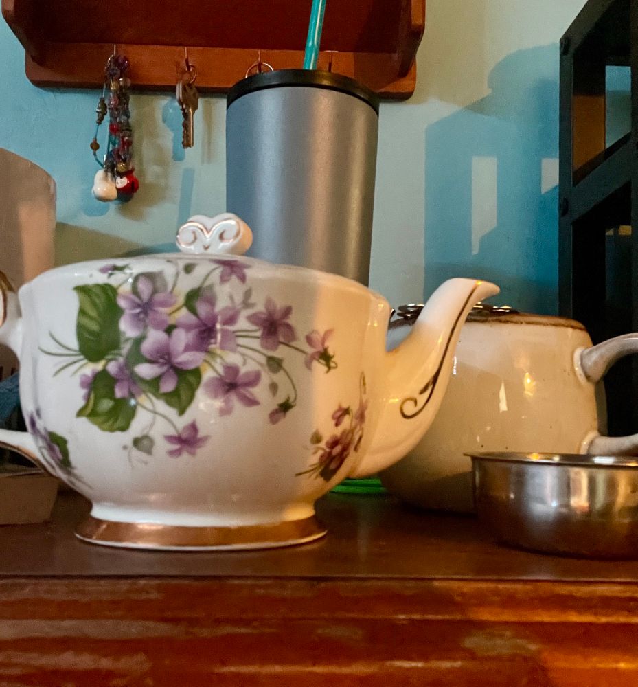 Purple floral pattern tea pot, round off white mug and tea strainer 
