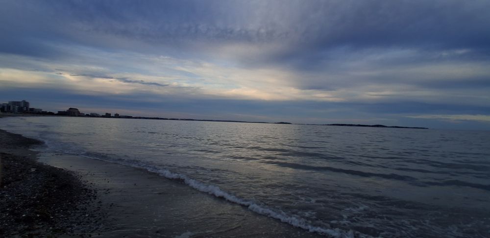 A photo of a large beach with light waves at sunset