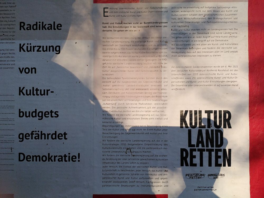 A wall newspaper features an article headlined "Radical cuts in cultural budgets endangers Democracy"