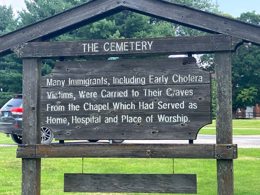 The back of the sign reads “THE CEMETERY: Many Immigrants, Including Cholera Victims, Were Carried to Their Graves From the Chapel Which Had Served as Home, Hospital, and Place of Worship.”
