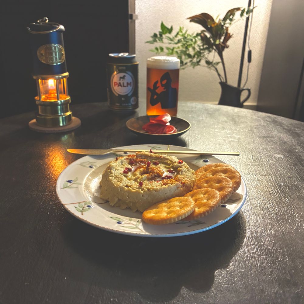 フムスに　クラッカーを添えたものを　食べながら、ビールを飲むところの　写真。紅芯大根の　甘酢漬けが　別皿にある。フムスには、クミン、にんにく、塩、オリーブオイルを　使っていて、上に　オリーブオイル、パプリカ、ピンクペッパーを　あしらった。
