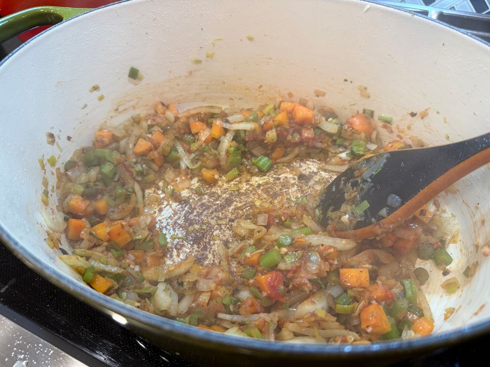 The veggie pile has cooked down some, leaving a dark brown fond on the bottom of the Dutch oven. There’s a bit of red tomato paste visible. 