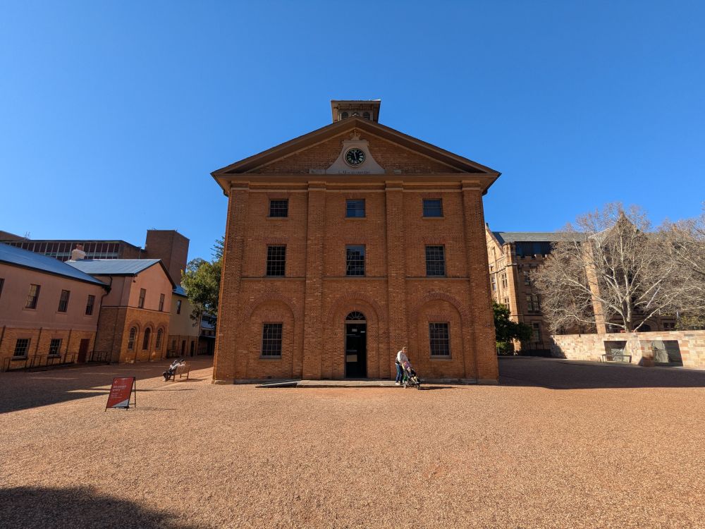 The front of hyde park barracks (early 19th century) brick built building for housing convicts, in a large open courtyard with gravel.