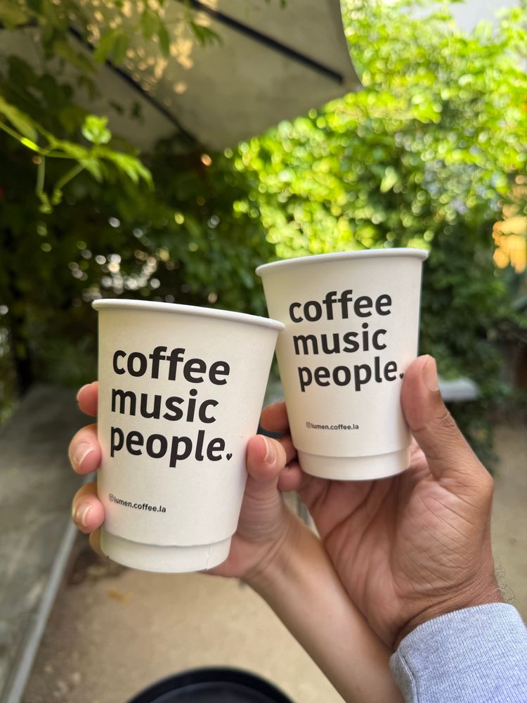 Two hands holding coffee cups that say ‘coffee music people.’