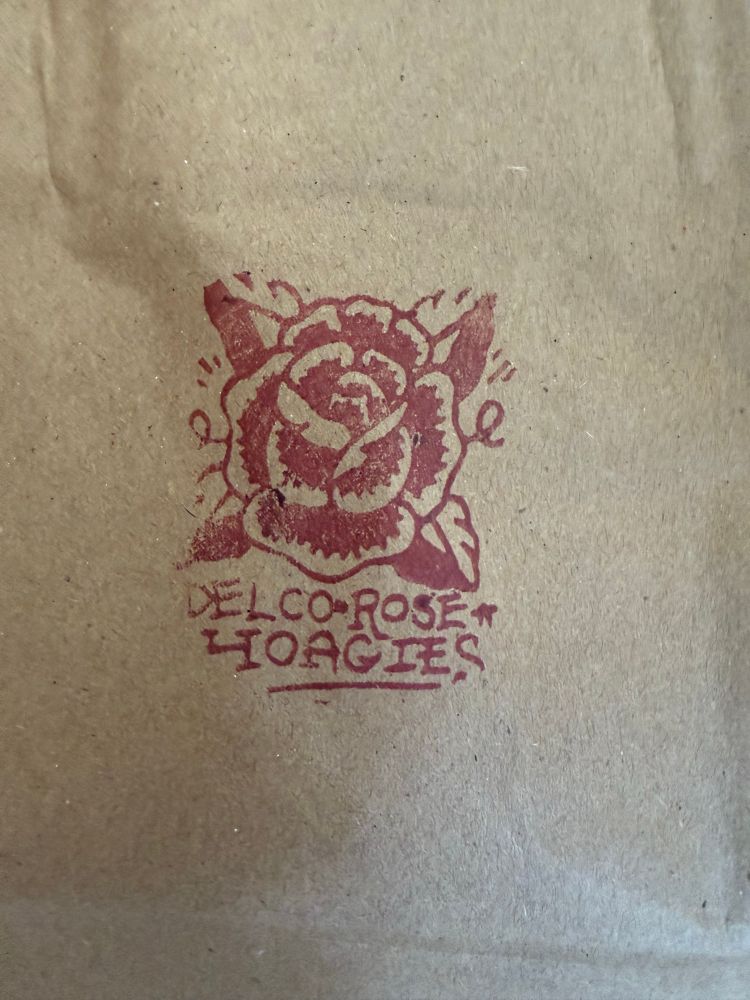 A logo stamped on a brown bag for a deli called Delco Rose Hoagies