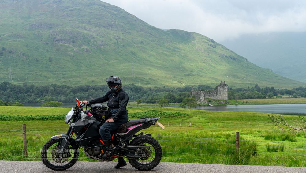 A candid photo of me standing beside my motorbike, Robin, with the ruins of Kilchurn Castle and Loch Awe in the background. The shot was kindly taken by a stranger who offered to help. The 15th-century castle sits against a backdrop of misty Highland hills and calm water, with the faint sound of bagpipes playing nearby, capturing the spirit of the Scottish landscape and the warmth of a spontaneous connection on the road.