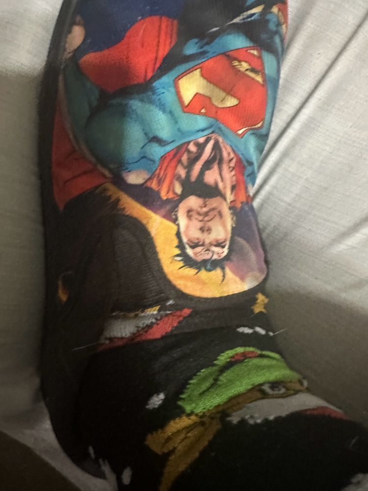 Canvas shoes with a Jim Lee Superman coupled with black socks with TMNT heads capped with a Santa hat. 