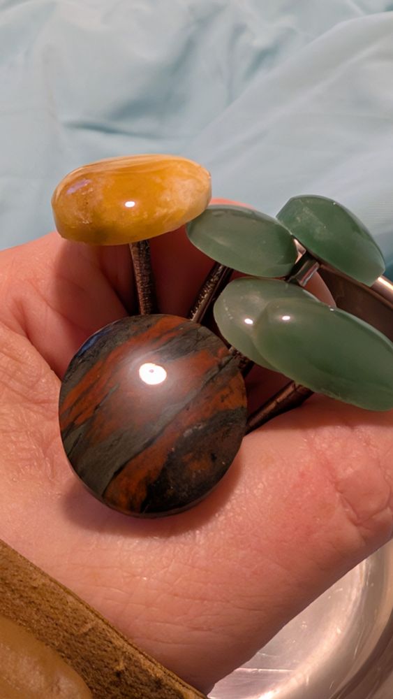 6 freshly made cabochons, still glued to the nails I used to hold onto them while shaping. 4 green aventurine, one yellow quartz and one banded iron formation
