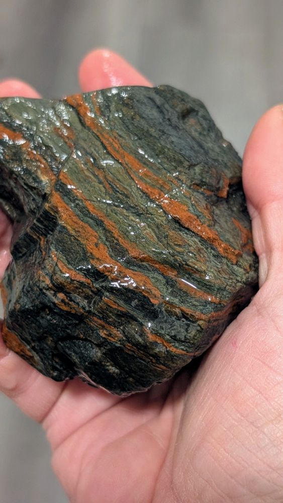 A palm sized chunk of banded iron formation, black, gray and red striped