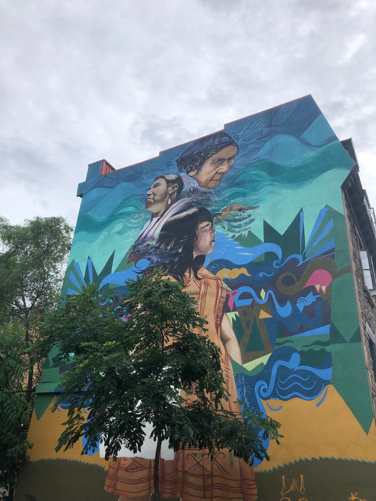 A mural depicting three Indigenous women (possibly a grandmother, mother, and daughter).
