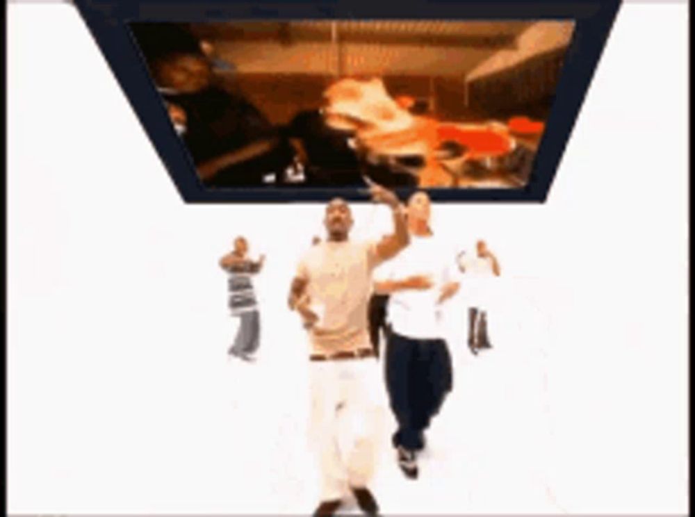 two men are dancing in front of a tv screen that has a pizza on it