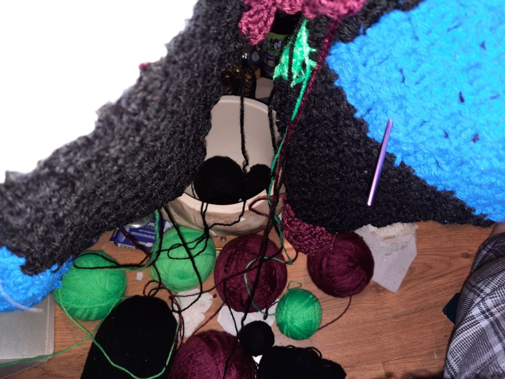 A section of crocheted blanket with 11 balls of yarn attached