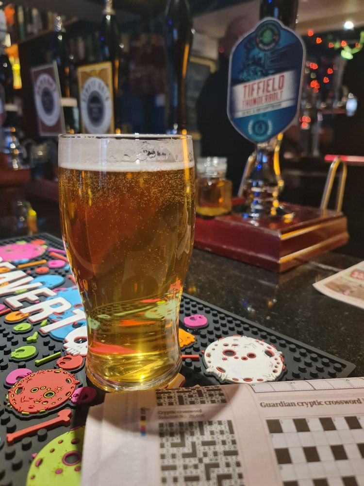 A pint of beer and a crossword on the bar in a pub