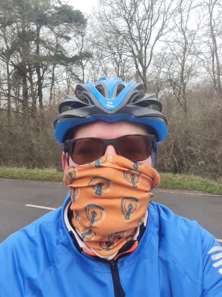 Head and shoulders of a cyclist wrapped up against the cold, wearing a helmet, face covering and waterproof jacket.