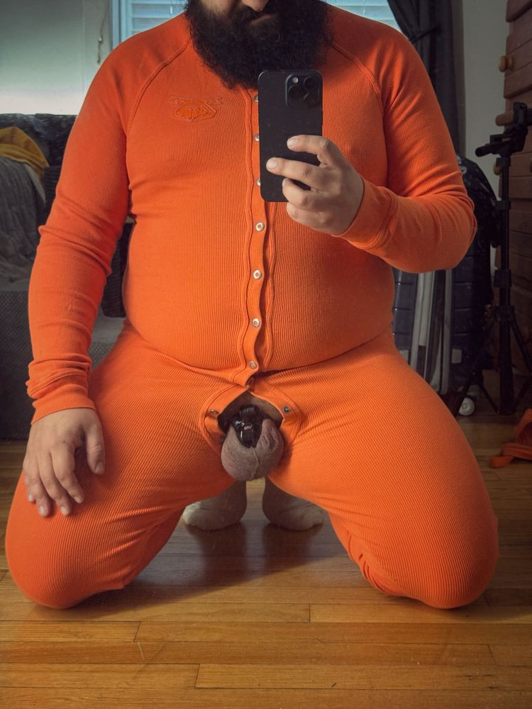 Photo of me in the mirror from the neck down. I’m wearing a bright orange union suit and my locked nub is pulled out of the fly 