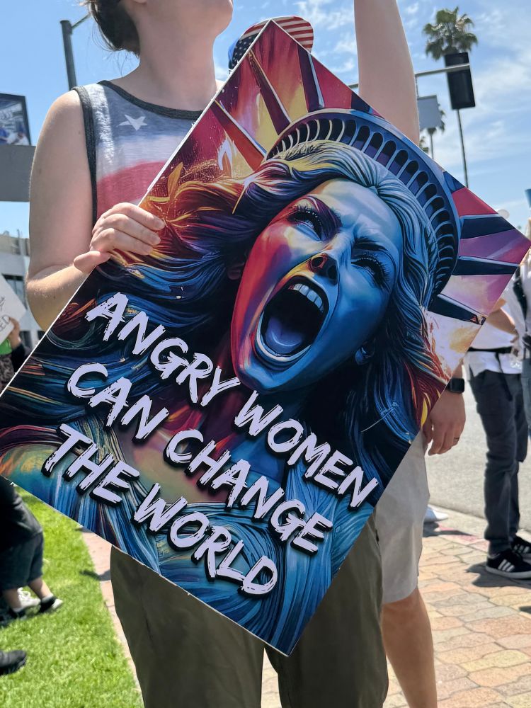 A protester on #NoKings day holds a sign that reads “Angry Women Can Change The World”