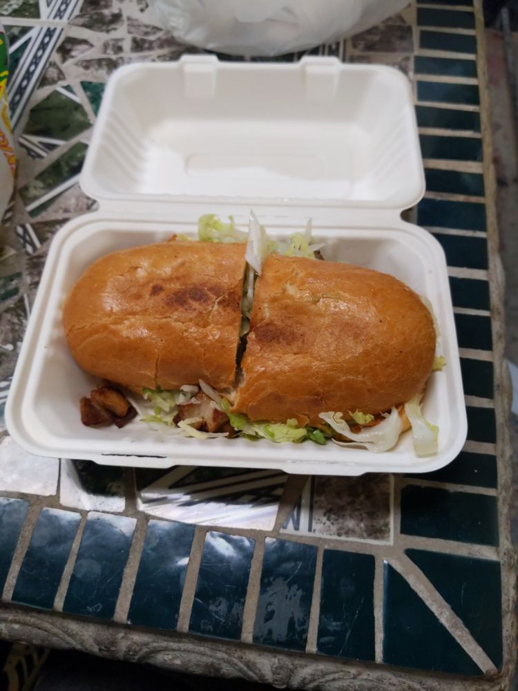 carnitas torta. lots of lettuce and guac. yummy toasted bread. styrofoam container