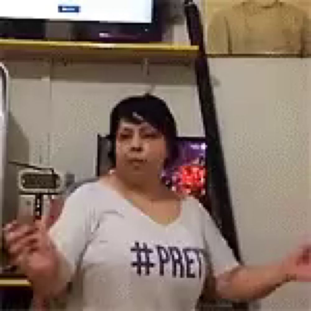 a woman wearing a white t-shirt with the word pret on it is standing in a room .