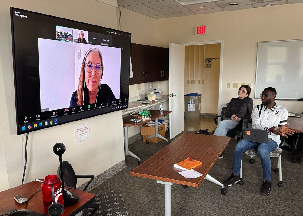 Photo of Danielle Arigoni on TV screen speaking with graduate students at Ohio University