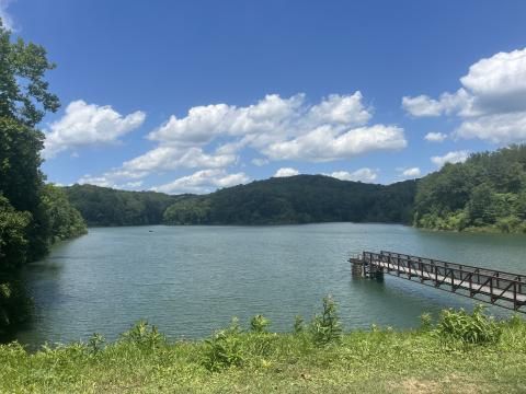 Photo of Dow Lake Dam in Athens Ohio with blue sky, white clouds, and a   structure extending out into the lake