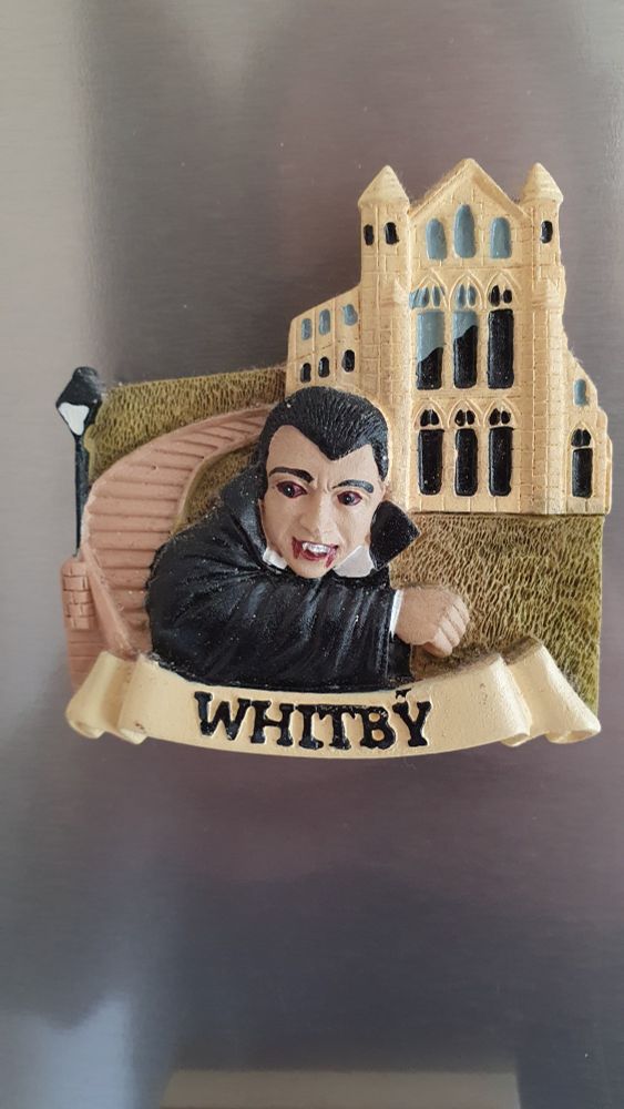 A cheap fridge magnet depicting Dracula outside of Whitby Abbey, with "WHITBY" on a scroll beneath. It is painted plaster, bought from a souvenir shop, and is charming in its naffness. 