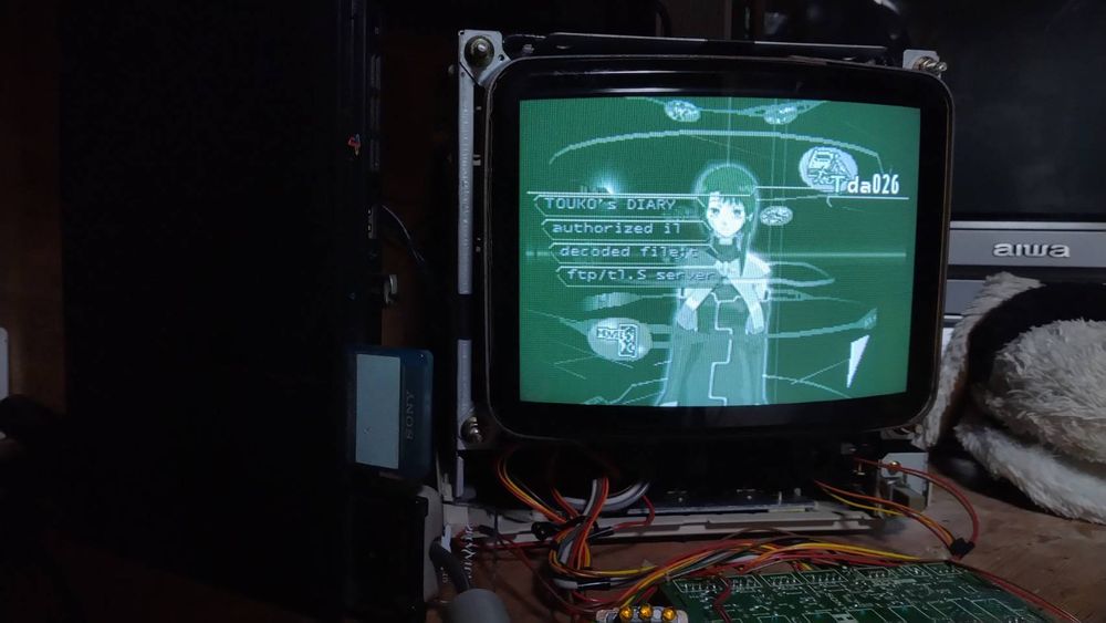A ps2 slim next to a partially disassembled trinitron monitor, playing ps1 serial experiments lain