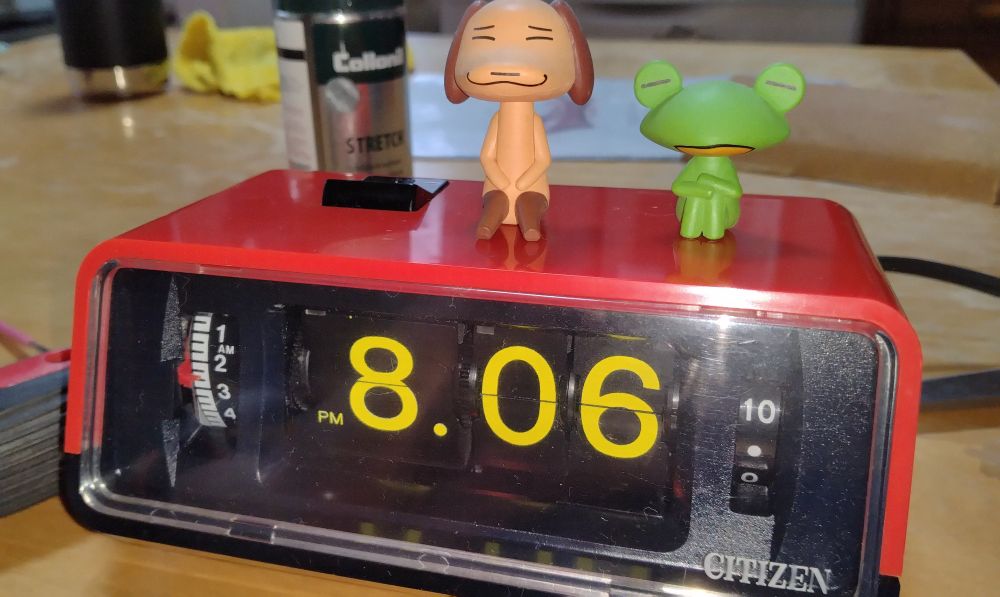 A red desk flip clock made by Japanese watch maker citizen
Pierre and Ricky from doko demo issyo sitting on top of the clock 