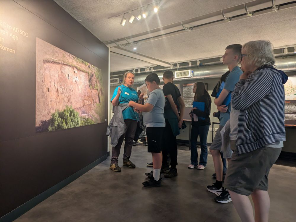 Group of people stood looking at a trench photograph in museum 