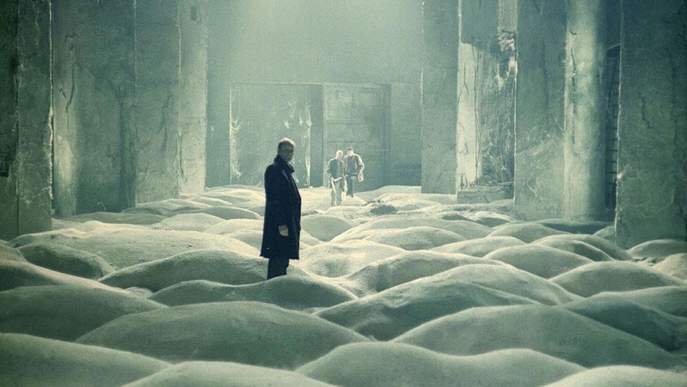 Une image d'une scène de Stalker de Tarkovski où 3 hommes sont debout à l'intérieur d'une mystérieuse ruine où le sol ressemble à un océan figé. 
A picture of Tarkovski's Stalker where three men stand in a mysterious ruin whose floor seemms made of frozen waves