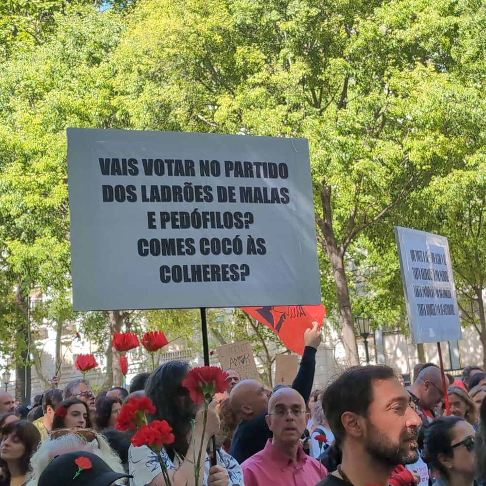 25 de Abril march along Avenida da Liberdade, a sign says "vais votar no partido dos ladrões de malas e pedófilos? comes cocó às colheres?"