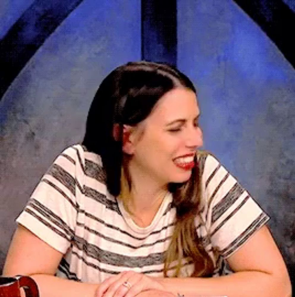 a woman wearing a striped shirt and a ring on her finger smiles