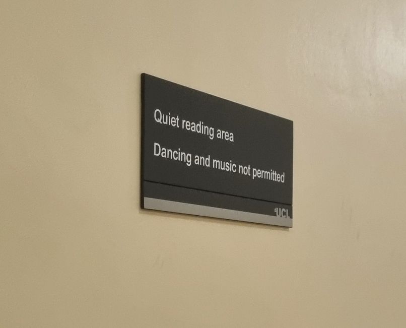 A sign on a cream wall reading 'Quiet reading area. Dancing and music not permitted'