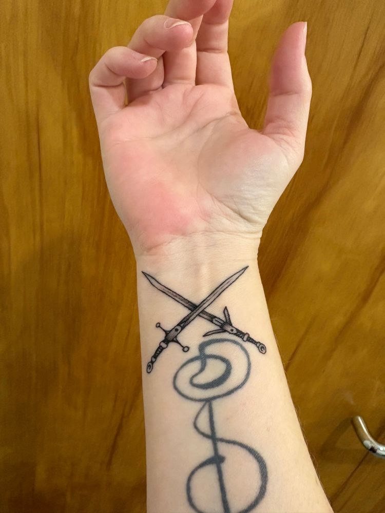 A fresh wrist tattoo of two Witcher swords right above an old long healed tattoo in Vulcan because I guess I’m just a big ol’ dork. 
